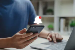 a young man using his phone with a danger alert showing on his screen