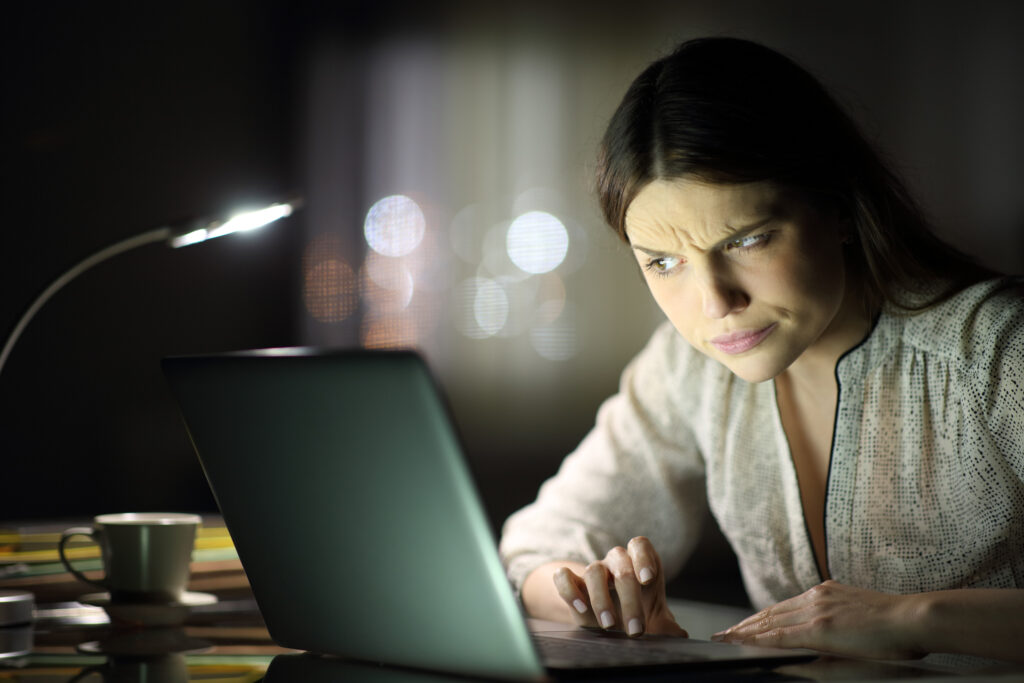 a woman looking suspicious while looking at her laptop during the night