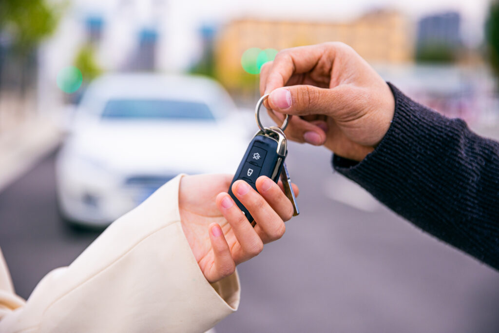 a person handing another person keys to their new car