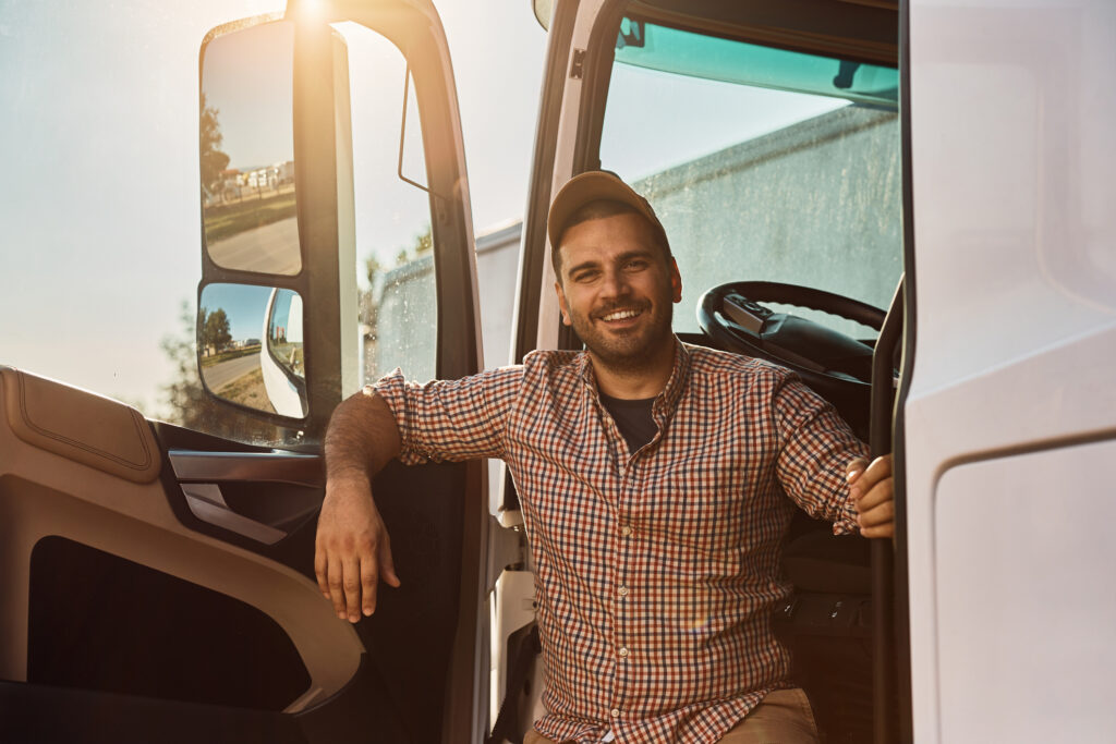 a happy truck driver leaning out of his truck